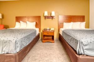a hotel room with two beds and a night stand at Zanesville Inn in Zanesville