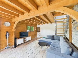 a living room with a blue couch and a tv at Cozy chalet with Nordic bath in Plancher-Bas
