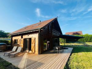 a house with a deck with a table and chairs at Cozy chalet with Nordic bath in Plancher-Bas