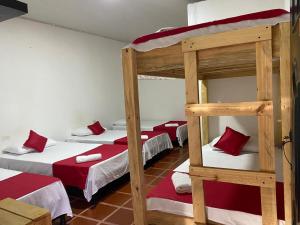 a room with three bunk beds with red and white sheets at Cabañas Spacetatacoa in Villavieja +26 photos