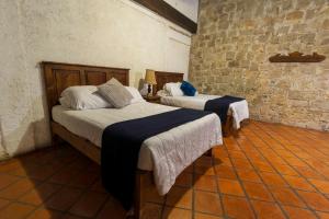 a bedroom with two beds and a brick wall at Casa Huitsiki in Cuetzalán del Progreso