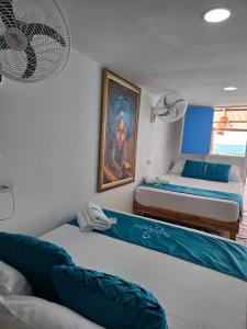 a bedroom with two beds and a painting on the wall at Santorini Barú in Playa Blanca +25 photos