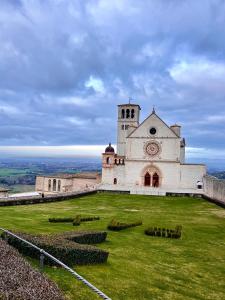 a building on top of a grassy hill with a clock tower at Il sentiero per Assisi in Bastia Umbra