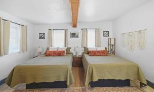 two beds in a room with white walls and windows at Dam Site Lodging in Truth or Consequences