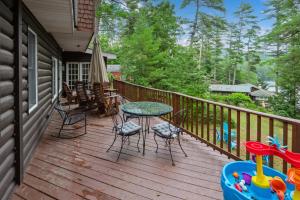 a wooden deck with a table and chairs at Adirondacks in Style! Lake House w/ Deck, Fire Pit in Hadley