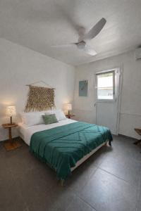 a bedroom with a large bed and a ceiling fan at Les bonites carbet pieds dans l eau in Le Carbet