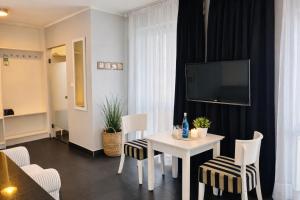 a living room with a table and chairs and a tv at HOTEL Amber Suite & SPA - Enklawa dla Dorosłych in Międzywodzie