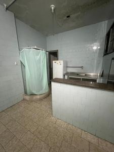 an empty kitchen with a tiled floor and a refrigerator at Vana Hostel Familiar in Fortaleza