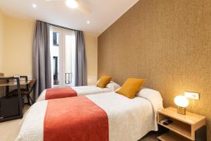 a bedroom with two beds and a desk and a window at Cálamo Guesthouse in Madrid