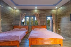 two beds in a room with two windows at Thiên Vy Homestay in Phú Quốc
