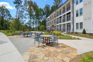 a patio with tables and chairs in front of a building at Landing Modern 2BD Gym Pool in Cornelius