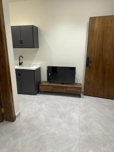 a room with a flat screen tv and a door at مسكن ترف للشقق الفندقية in Al Majma'ah