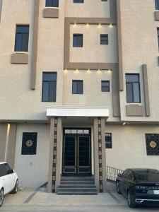 a building with two cars parked in front of it at مسكن ترف للشقق الفندقية in Al Majma'ah