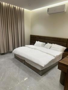 a bedroom with a large bed with white sheets at مسكن ترف للشقق الفندقية in Al Majma'ah +6 photos