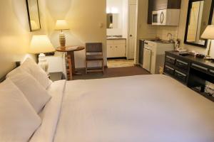 a bedroom with a large white bed and a kitchen at Chalet Inn in Kitimat