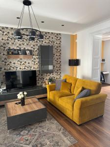 a living room with a yellow couch and a tv at Apartman Golden in Senta