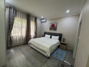 a bedroom with a white bed and a window at Sable Suites C1, 1 Bed Apartments in Kabulonga in Lusaka +18 photos