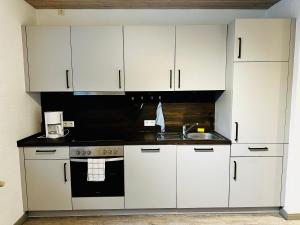 a kitchen with white cabinets and a sink at Charmante FeWo in Dorflage in Ebersdorf