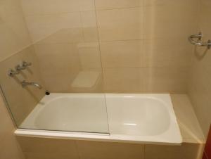 a bathroom with a shower with a white tub at Malaika in Puerto Madryn