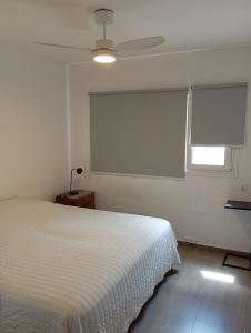 a bedroom with a white bed and a window at Malaika in Puerto Madryn