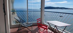 two chairs and a table on a balcony with a view of the water at Appartement Le Cap in Toulon