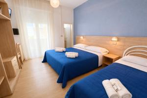 a hotel room with two beds with blue sheets at Hotel Damma's, Dipendenza Zamagna in Cesenatico