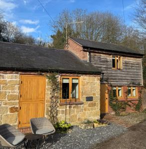 an old stone house with two chairs in front of it at Woodland, Canal & Lakeside Cottage in Ellesmere