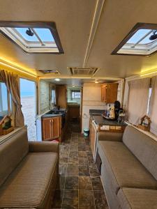 Innenansicht eines Wohnmobils mit Sofas und Küche in der Unterkunft dhabab caravan كرفان ضباب in Ḑibāb
