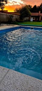 a blue swimming pool with a sunset in the background at La Gualeyita in Gualeguay