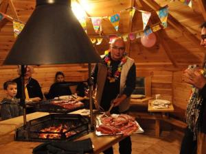 a man standing in front of a grill with meat at Charmante Cabane 5 Pers, Chauffée - API-1-52-1704 in Champvert
