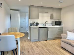 a kitchen with white cabinets and a table and a couch at Ballyaghran Stay in Portstewart