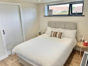 a bedroom with a white bed and a window at Ballyaghran Stay in Portstewart