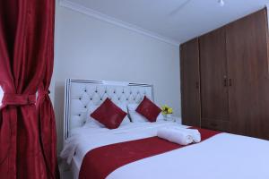 a bedroom with a large white bed with red pillows at Lola Homes Thika in Thika