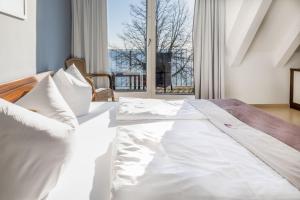 a white bed in a room with a large window at Strandhotel Dranske in Dranske