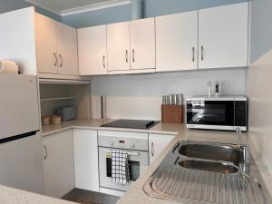 a kitchen with white cabinets and a sink at Howrah Apartment in Howrah