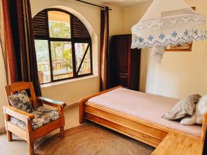a bedroom with a bed and a chair and a window at Villa Media in Kigali