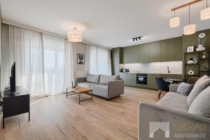 a living room with a couch and a tv at Fuzja II by LookAp in Łódź