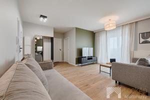 a living room with a couch and a television at Fuzja II by LookAp in Łódź