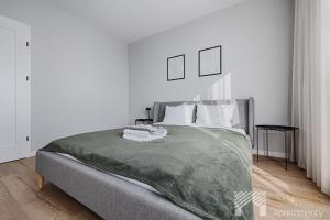 a white bedroom with a bed with a green blanket at Fuzja II by LookAp in Łódź