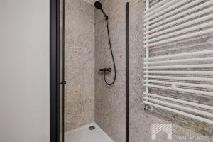a shower with a black shower head in a bathroom at Fuzja II by LookAp in Łódź +18 photos