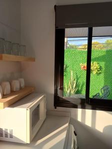 a kitchen with a microwave and a window at Confort urbano - Departamento de 1 dormitorio con cochera in Venado Tuerto