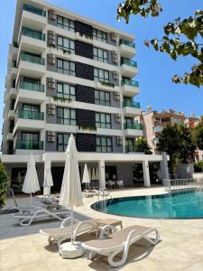 a hotel with chairs and a swimming pool and a building at SA Apartments! 150m to the Cleopatra Beach in Alanya
