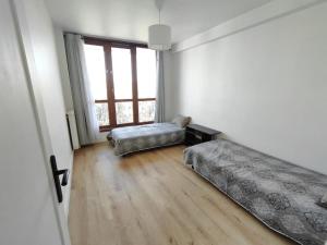 a bedroom with two beds and a large window at Appartement spacieux in Argenteuil