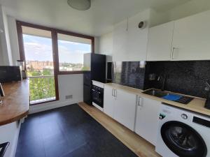 a kitchen with white cabinets and a large window at Appartement spacieux in Argenteuil
