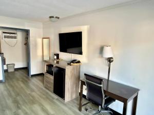a hotel room with a desk and a flat screen tv at Budget Inn Conway in Conway