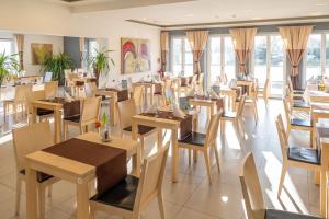 a restaurant with wooden tables and chairs and windows at Strandhotel Dranske in Dranske