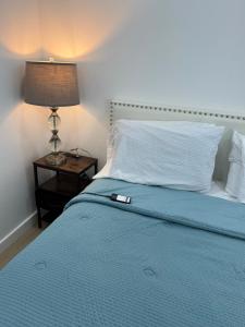 a bed with a blue blanket and a lamp on a table at Comfy and Relaxed in Cutler Bay +29 photos