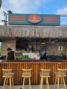 a man standing behind a bar with four chairs at Apartamento em Arraial do Cabo in Arraial do Cabo +70 photos