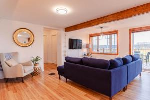 a living room with a blue couch and a chair at Hôtel à la maison - La Bleue Maritime in Rivière-du-Loup