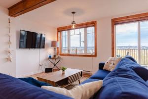 a living room with a blue couch and a tv at Hôtel à la maison - La Bleue Maritime in Rivière-du-Loup +29 photos